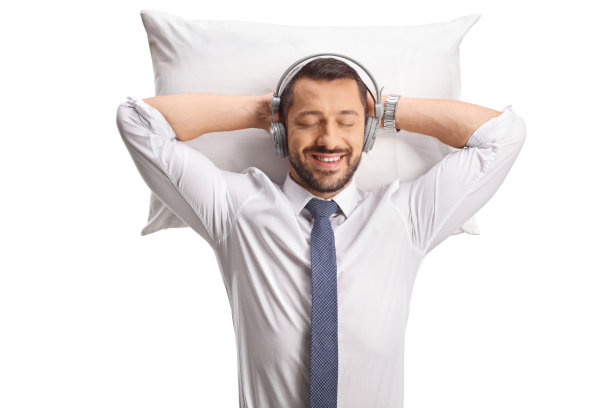 戴着耳机睡在枕头上的放松商人图片下载