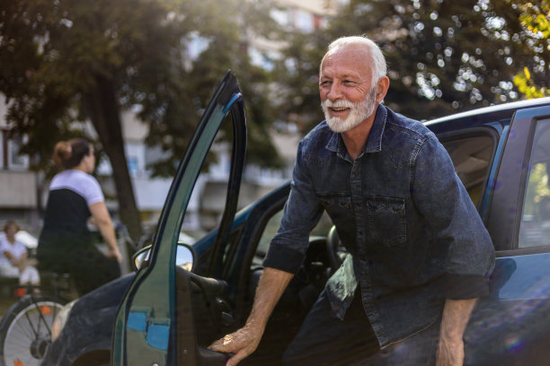 照片中，一位老人在自然的阳光下从一辆现代汽车里出来。一个快乐的商人从他的现代汽车里走出来，面带微笑。图片下载