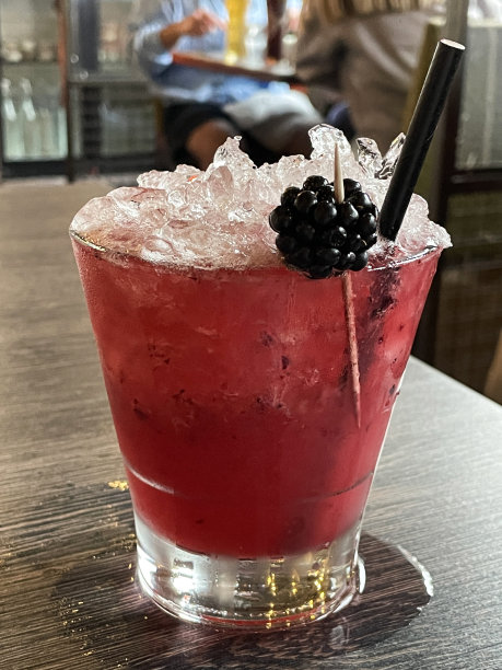 酒吧设置的特写图片，喝一杯加冰的黑莓鸡尾酒，黑莓鸡尾酒棒和黑纸吸管，桌子，焦点在前景图片下载