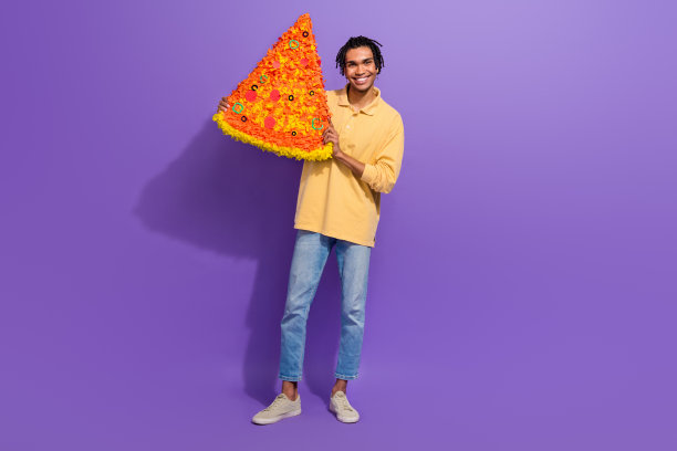 友好的男生学生的全身照片，订购便宜的披萨，切片意大利大餐，在紫色的背景上孤立地吃着图片下载