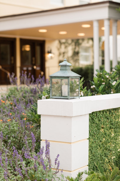 在佛罗里达州棕榈滩，被紫色和橙色的花朵和绿色环绕的室外混凝土墙上挂着质朴的蓝绿色灯笼图片下载