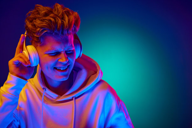 年轻人的肖像，学生穿着白色休闲装，戴着耳机听音乐，霓虹灯滤镜渐变薄荷背景。图片下载