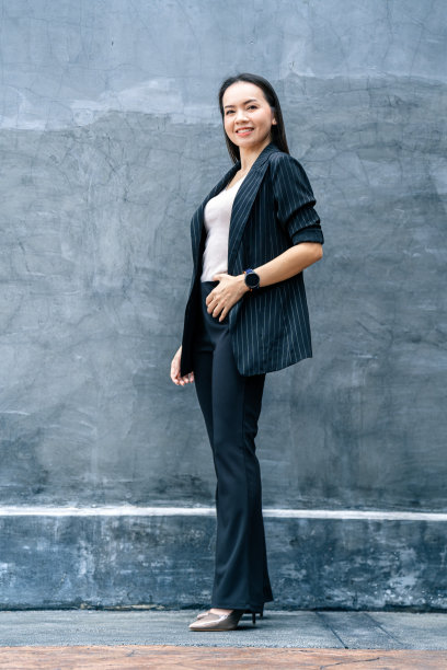 成功的商业亚洲妇女的肖像，黑色西装和微笑孤立在蓝色背景。商业库存照片。图片下载