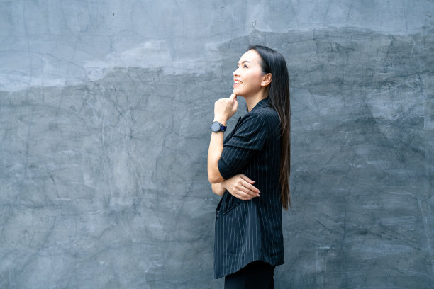 成功的商业亚洲妇女的肖像，黑色西装和微笑孤立在蓝色背景。商业库存照片。图片下载