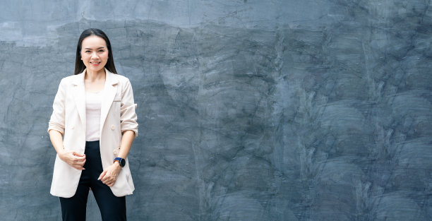 成功的商业亚洲妇女的肖像在灰色的西装和微笑孤立的蓝色背景。商业库存照片。图片下载