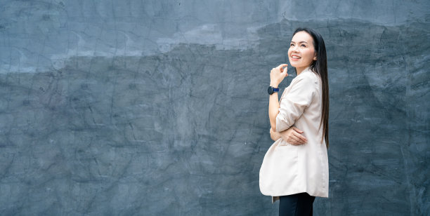 成功的商业亚洲妇女的肖像在灰色的西装和微笑孤立的蓝色背景。商业库存照片。图片下载