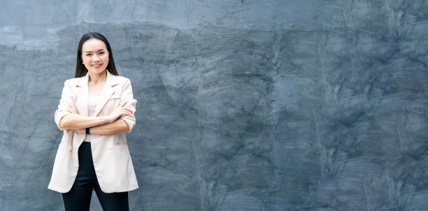 成功的商业亚洲妇女的肖像在灰色的西装和微笑孤立的蓝色背景。商业库存照片。图片下载
