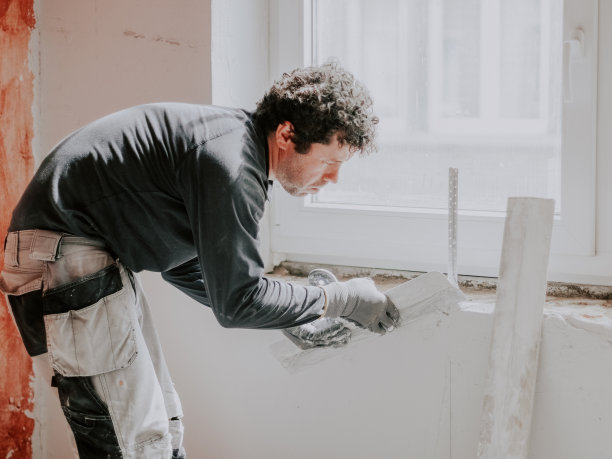 一个年轻人正在给墙上涂腻子。图片下载