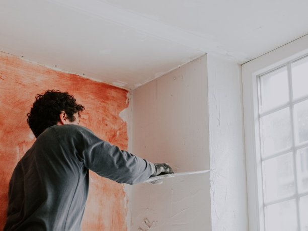 一个白人年轻人正在给墙上涂腻子。图片下载