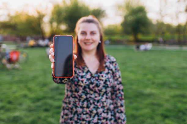 女孩使用智能手机分享社交媒体新闻，穿着风格时尚的时髦帽子在城市背景，夏天的时间，横幅模拟或照片图片下载