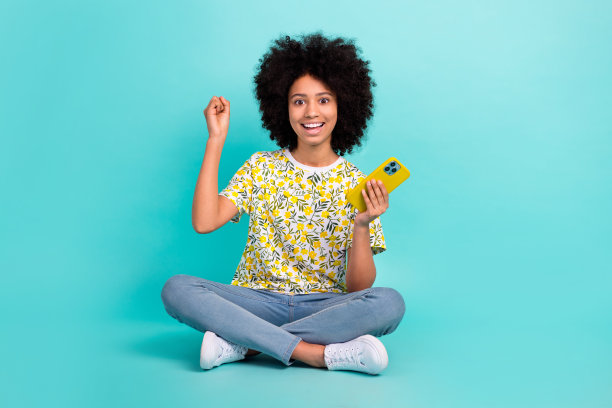 照片的喜出于色的兴奋疯狂的女孩穿着时髦的衣服，双手享受自由时间购物销售孤立的青色背景图片下载