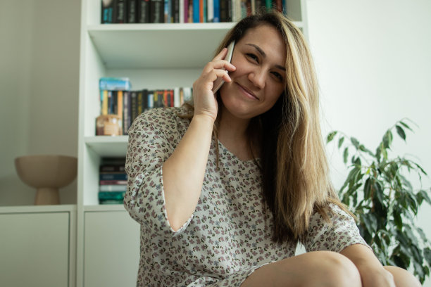 这张照片拍摄的是一名留长发的年轻女子坐在家里的客厅里打电话图片下载