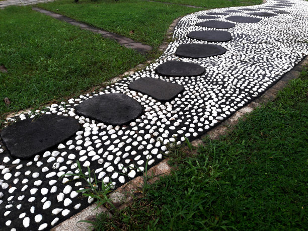 公园景观。白鹅卵石和黑石头组成了一条人行道。石头的道路。公园的道路。石头的道路。园林绿化，特写照片图片下载