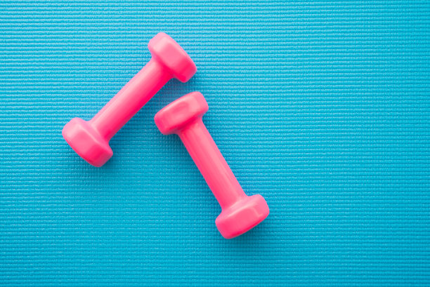 粉色哑铃在蓝色瑜伽垫背景上健身锻炼。图片下载