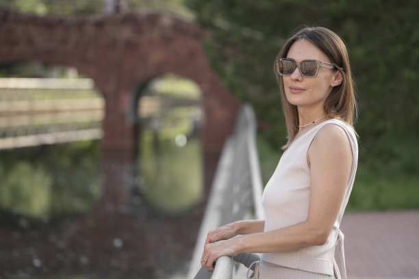 一个戴着墨镜的黑发女子的夏日都市肖像。这张照片是在黄金时段在背光下拍摄的。图片下载