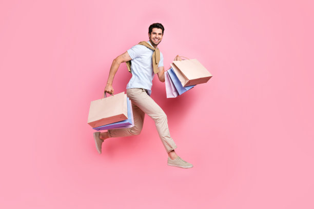 疯狂兴奋的人拿着购物中心的袋子跳跃冲向空白的粉红色背景的全尺寸头像照片图片下载