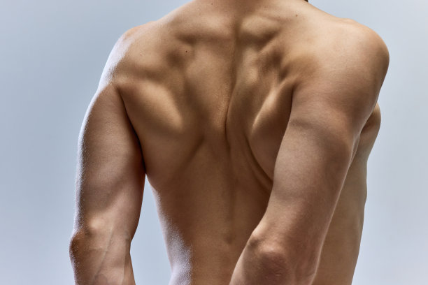 年轻运动员肌肉的特写照片，男模特在灰色的工作室背景下赤裸着上身。肌肉恢复。图片下载