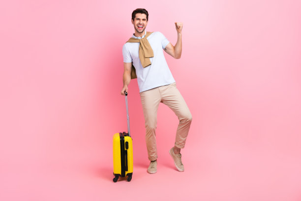 男子的全身照片，高举拳头，欢呼，庆祝他的胜利免费通票，旅行者携带的手提箱孤立在粉红色的背景图片下载
