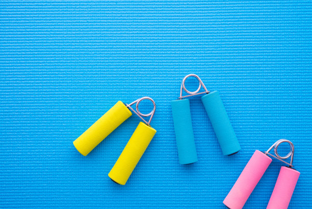 在蓝色瑜伽垫背景上健身运动的彩色健身软握。图片下载