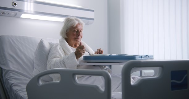 女老年病人一边吃着美味的食物，一边看着镜头图片下载