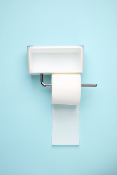 厕纸架上有一卷厕纸挂在蓝色的墙上。简约的照片图片下载