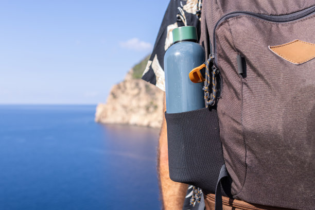 照片聚焦在一个以大海为背景的水壶的登山背包上。图片下载