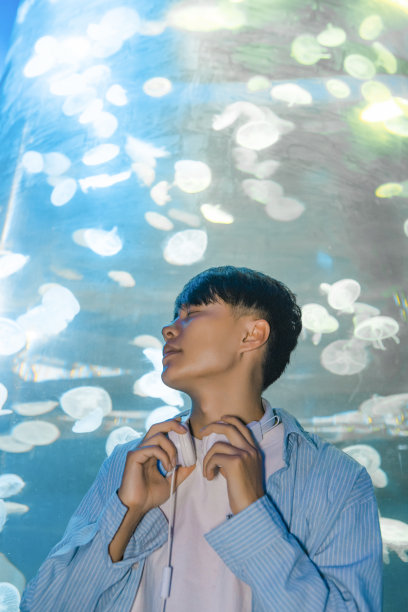 一个戴着耳机的人正在水族馆里观察海洋生物——周末活动、旅行生活、人和生物图片下载