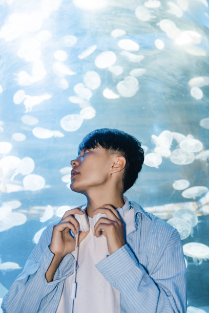 一个戴着耳机的人正在水族馆里观察海洋生物——周末活动、旅行生活、人和生物图片下载