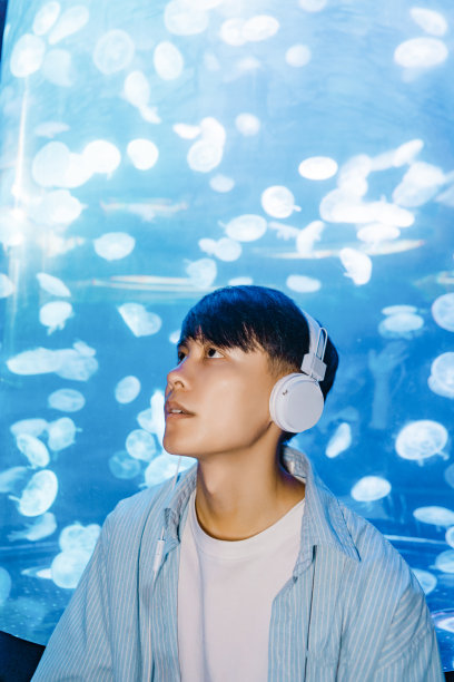 一个戴着耳机的人正在水族馆里观察海洋生物——周末活动、旅行生活、人和生物图片下载