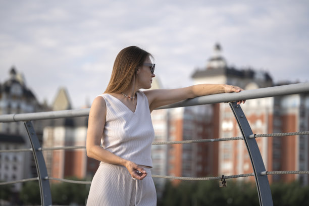 一个戴着墨镜的黑发女子的夏日都市肖像。这张照片是在黄金时段在背光下拍摄的。图片下载