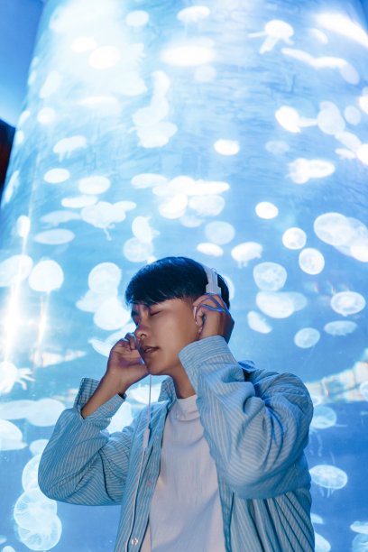 一个戴着耳机的人正在水族馆里观察海洋生物——周末活动、旅行生活、人和生物图片下载