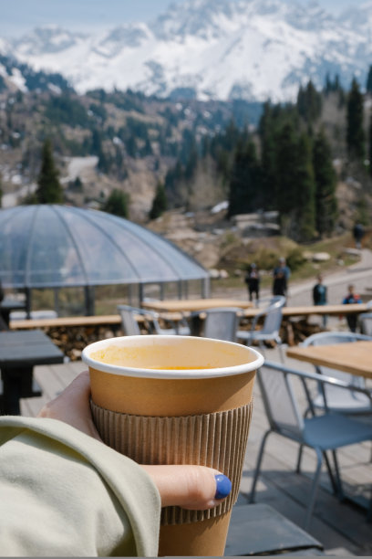 手持橙色水果茶杯与山的背景与复制空间为您的文字。高质量的垂直照片。图片下载