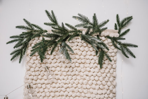 拱门由圣诞树的树枝做成，上面装饰着花环和大灯、灯泡。照片区，墙壁的织物棉质。室内阁楼风格。家里的圣诞装饰。寒假的概念。图片下载