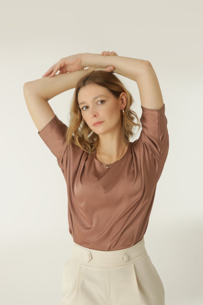 一系列的工作室照片的年轻女模特穿着简单美丽的服装，丝绸缎衬衫和白色阔腿裤图片下载