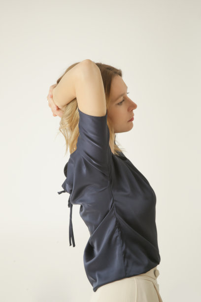 一系列的工作室照片的年轻女模特穿着简单美丽的服装，丝绸缎衬衫和白色阔腿裤图片下载