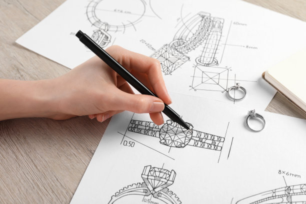 珠宝商在木桌的纸上绘制精美戒指的草图，特写图片下载