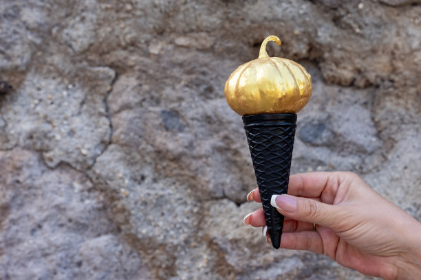 拿着一个金色的万圣节南瓜在华夫蛋筒里图片下载