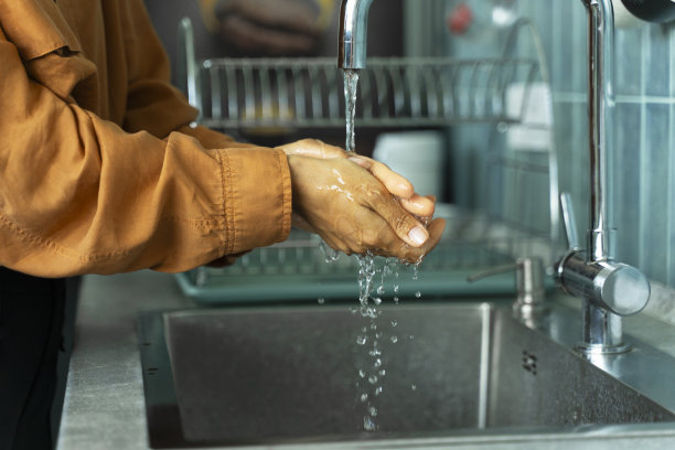 一名妇女在厨房水槽前做饭前洗手的照片。卫生的概念图片下载