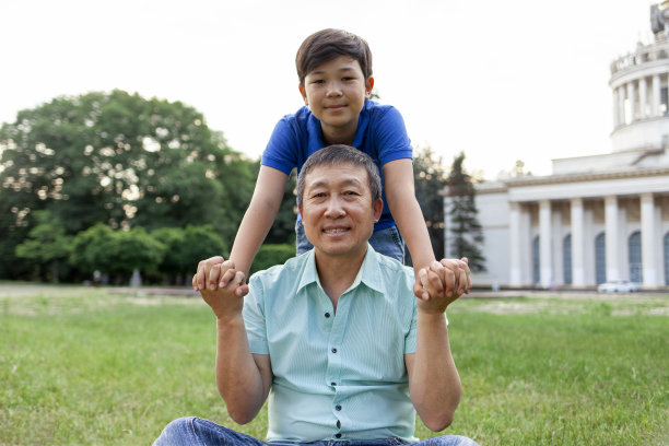 亚洲老父亲和小儿子在户外的照片，韩国男孩在公园里拥抱爷爷微笑图片下载