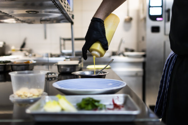 一只戴着黑色手套的手正在用酸橘汁腌鱼把锅里的酱汁倒在盘子里图片下载