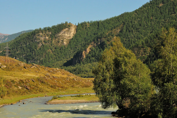 在一个温暖的夏夜，在一条流经山谷的美丽河流的河床上，倚着树木。图片下载