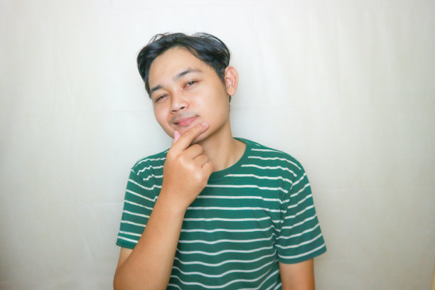 一名印尼亚裔男子身穿绿色衣服，以白色为背景，正在拍摄各种表情的照片图片下载