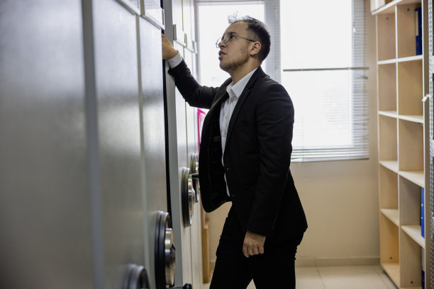 组织办公室:商人在金属书柜用活页夹检查登记文件图片下载