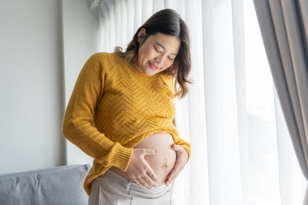 怀孕的亚洲妇女双手放在肚子上抚摸她的孩子，关心她的健康美丽快乐怀孕womanÂ温柔的心情怀孕照片图片下载