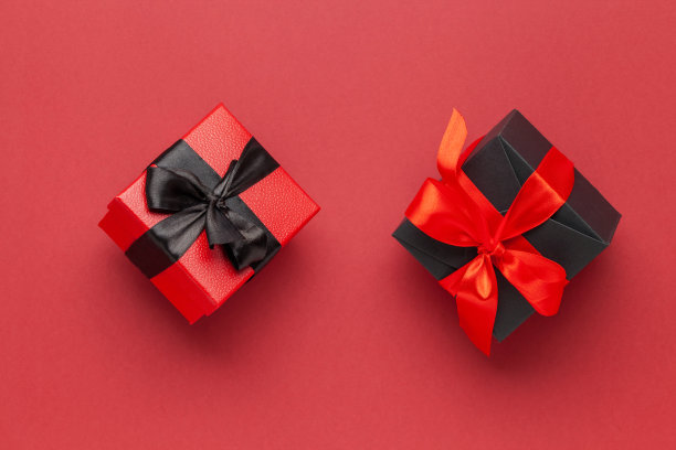 黑色的盒子，红色的蝴蝶结，暗红色的背景。双十一概念。网上购物销售。图片下载