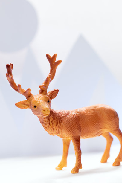 一个可爱的玩具驯鹿在纸冬天的风景背景。手工制作的月亮和山。圣诞景观。图片下载