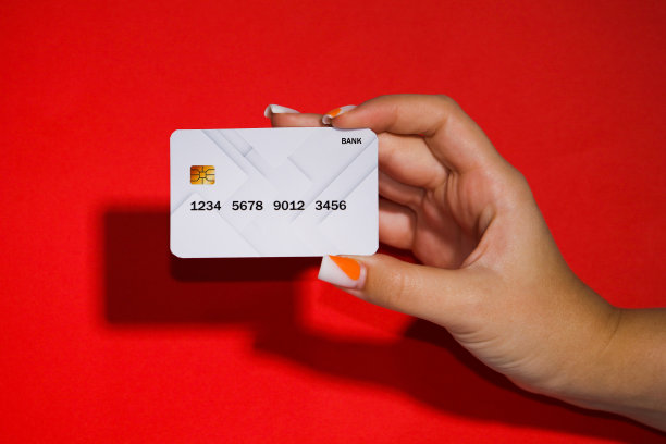 图片以红色为背景，一个女人手里拿着一张白色的银行卡，这是一种非常美丽和罕见的颜色。图片下载