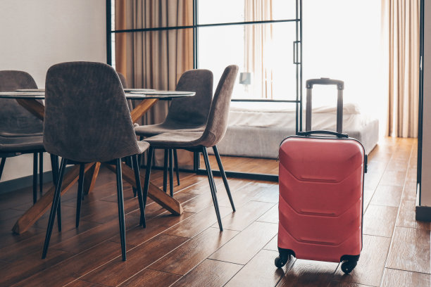 粉红色的手提箱放在浅色的旅馆房间里图片下载