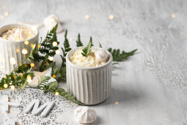 热巧克力杯，鲜奶油，白巧克力和梅伦格糖，白色纹理背景，蕨类叶子和金色散景。斯堪的纳维亚风格的圣诞节图片下载