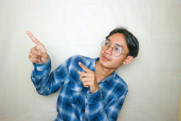 一名印尼亚裔男子身穿蓝色衣服，以白色为背景，正在拍摄各种表情的照片图片下载